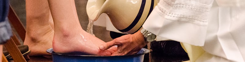 A Deacon washes the feet of a parishioner.